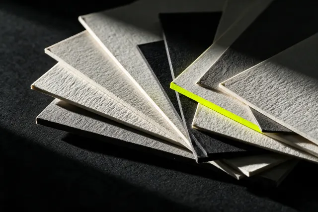 Illustrative photo: a fan of heavy textured paper samples, one with a lime edge